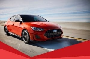 Hyundai Veloster flame red, driving on road, front right side view